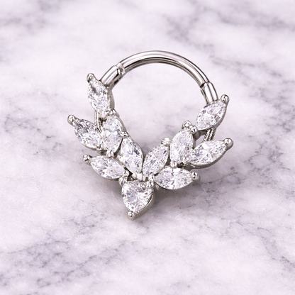 Silver septum ring with leaf-shaped gemstones on a marble background
