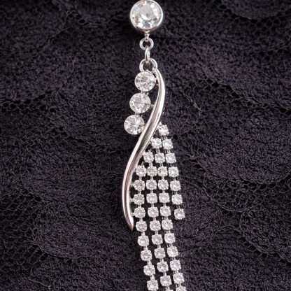 Silver navel bar with clear stones on a black textured background