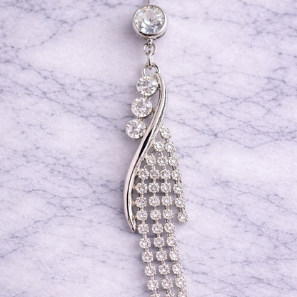 Silver navel ring with clear stones on a marble background