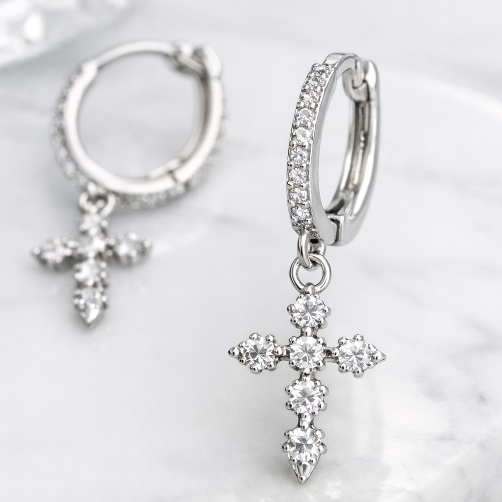 Silver hoop earrings with cross pendants on a white shell background