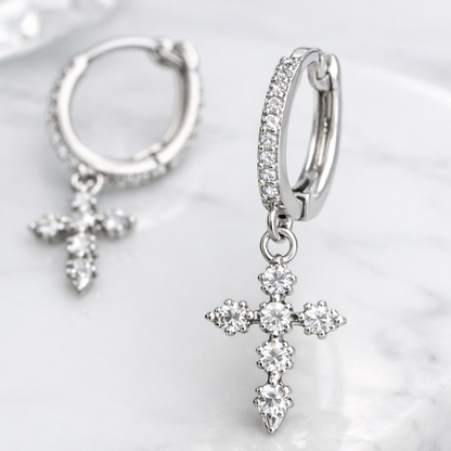 Silver hoop earrings with cross pendants on a white shell background