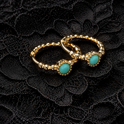 Gold ring with turquoise stones on a black lace background
