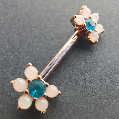 Delicate floral nipple piercing barbell with a white flower design, blue CZ stone, and rose gold finish.