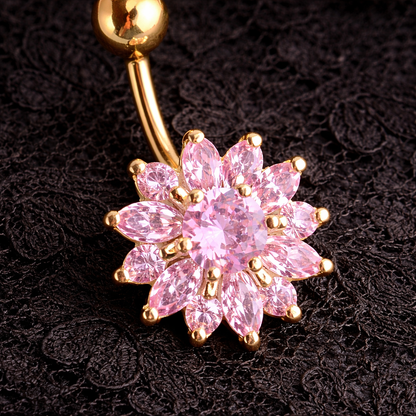 Gold belly button ring with pink gemstones on a dark textured background