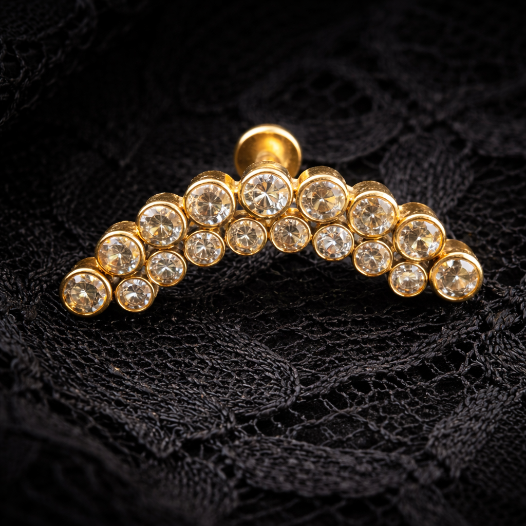 Gold titanium earring with clear gemstones on a black lace background