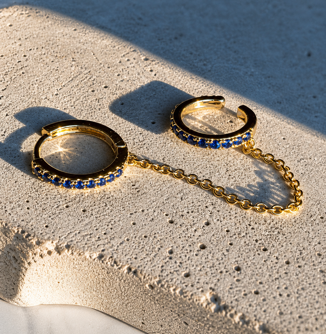 Gold and blue beaded earrings on a textured surface