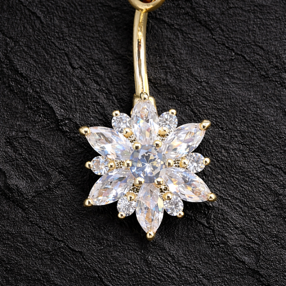 Gold belly button ring with a flower-shaped diamond design on a black background
