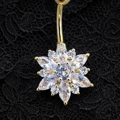 Gold belly button ring with a flower shaped clear gemstone on a black lace background