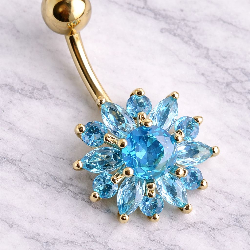 Gold belly button ring with blue gemstones on a marble background