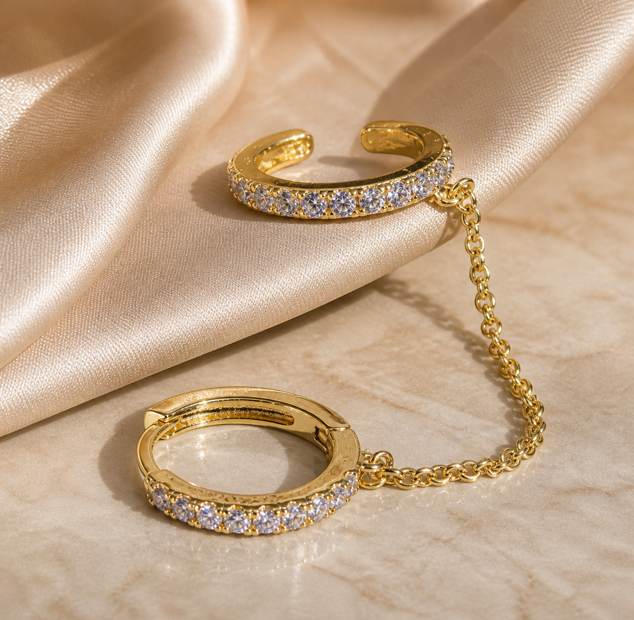 Gold bracelet with chain and ring on a beige fabric background