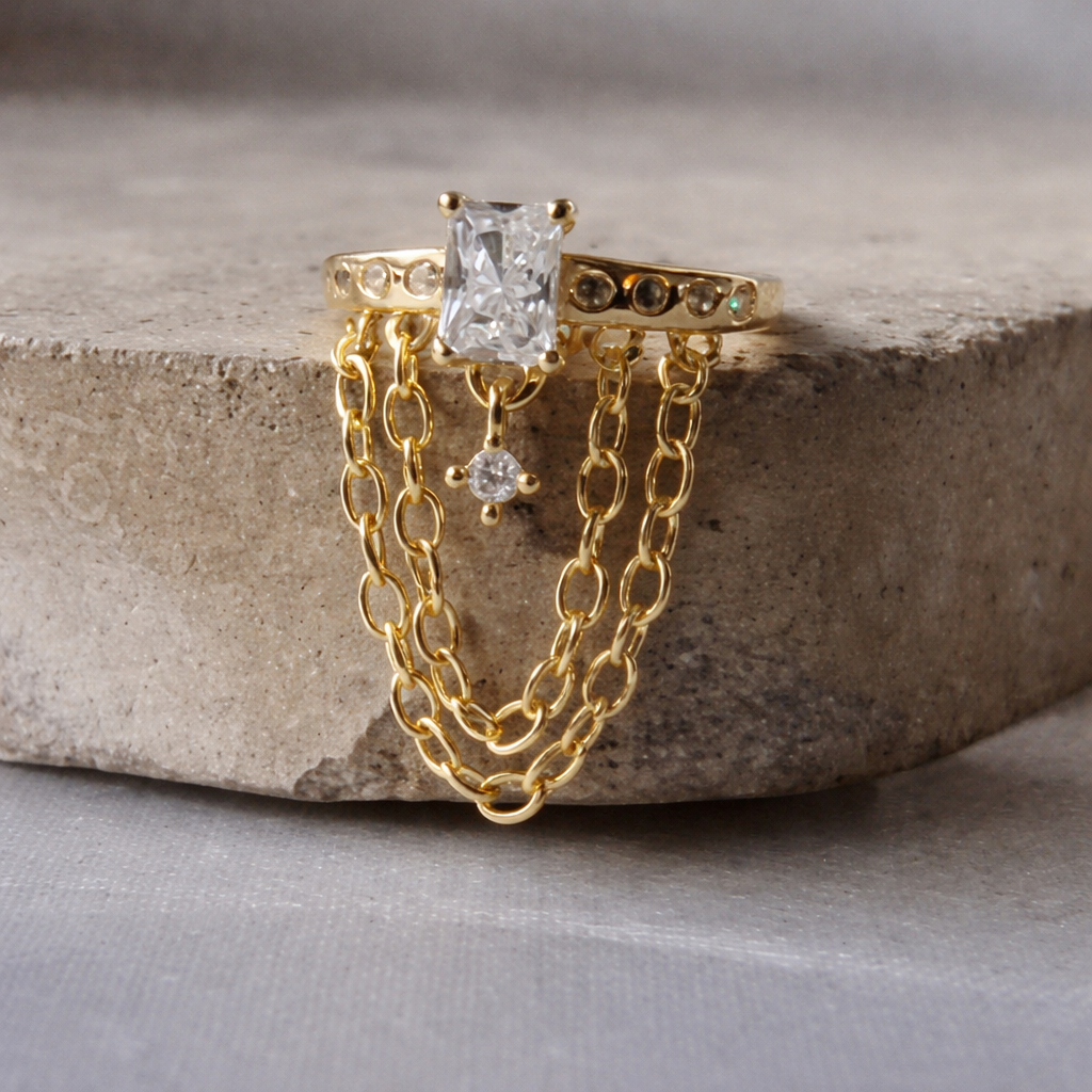 Gold chain ring with a central diamond and smaller diamonds on a stone surface