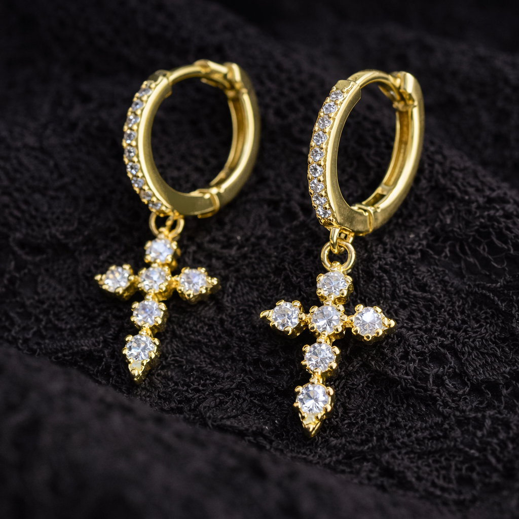 Gold hoop earrings with cross designs on a black textured background