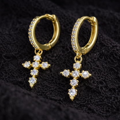 Gold hoop earrings with cross designs on a black textured background