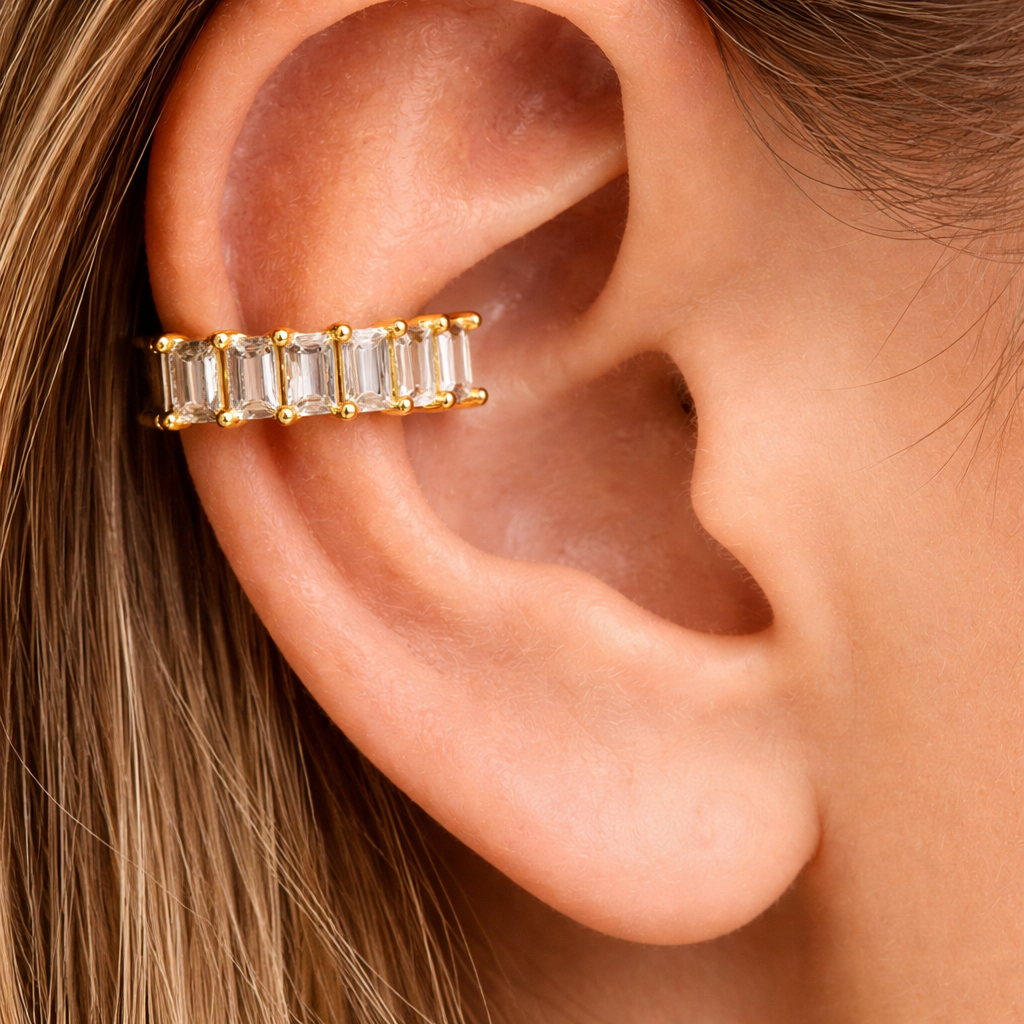 Gold earring with clear stones worn on an ear