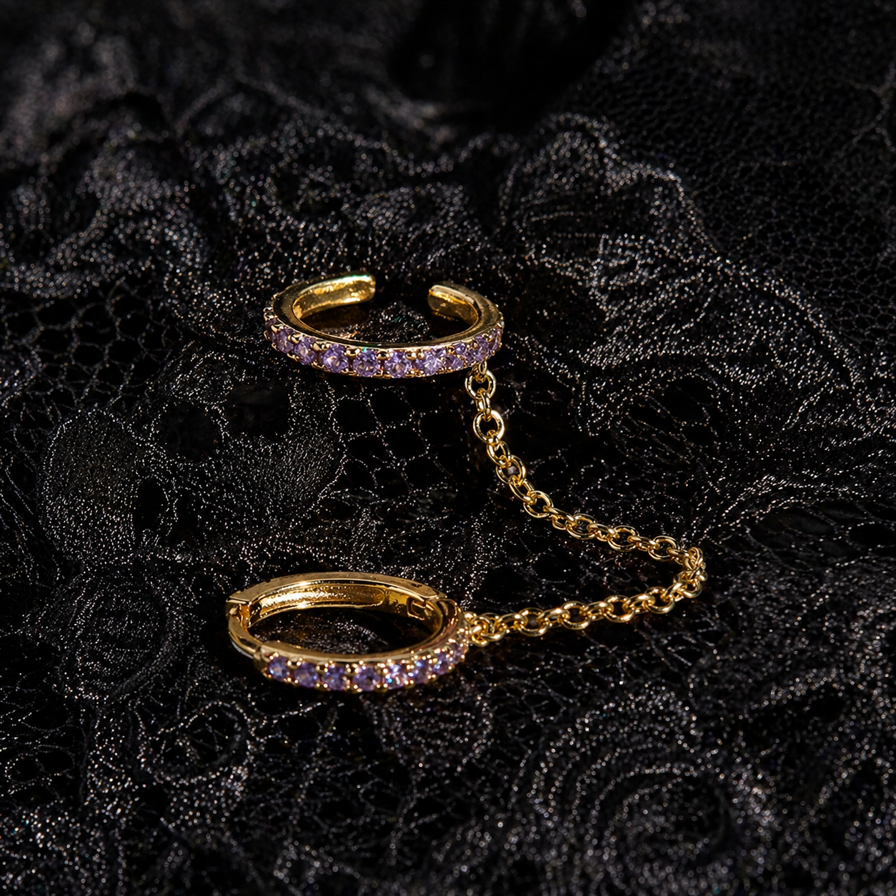 Gold ear cuff with purple gemstones on a black textured background