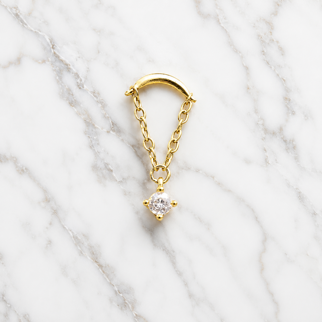 Gold earring with a diamond on a marble background