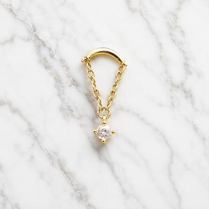 Gold earring with a diamond on a marble background