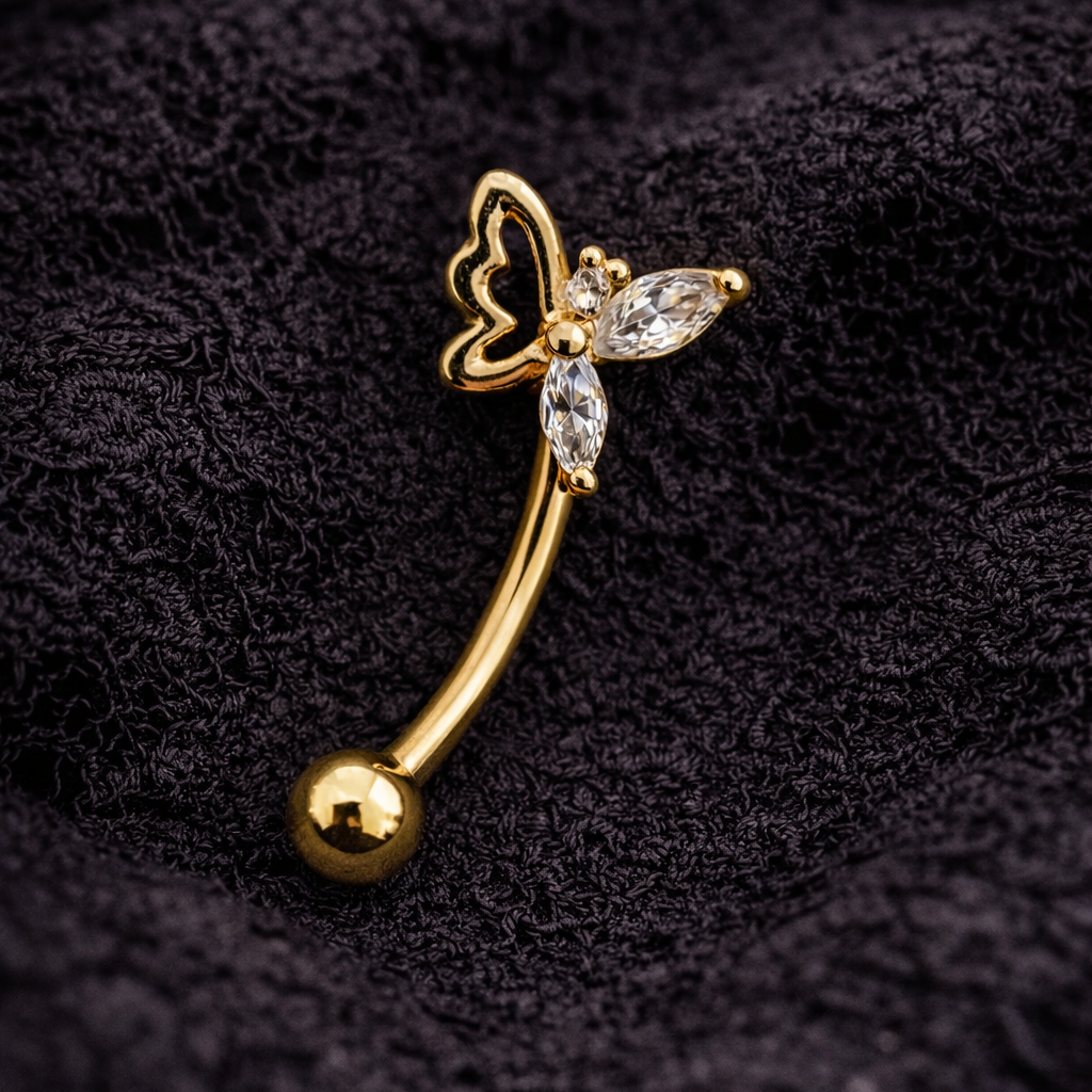 Gold eyebrow/rook bar with butterfly design on a black textured background