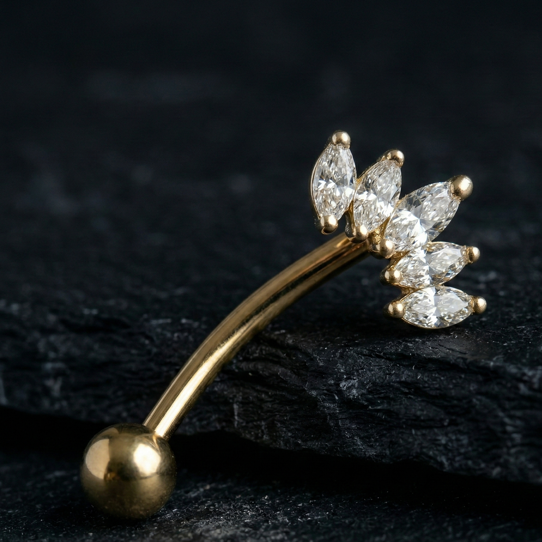 Gold eyebrow/rook bar with crown diamond-like stones on a dark surface