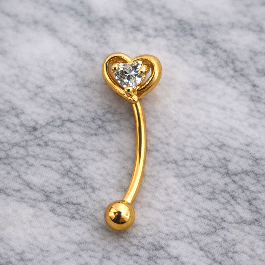 Gold eyebrow/rook bar with heart design on a marble background