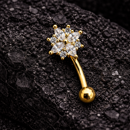 Gold eyebrow/rook bar with star-shaped gemstones on a black textured background