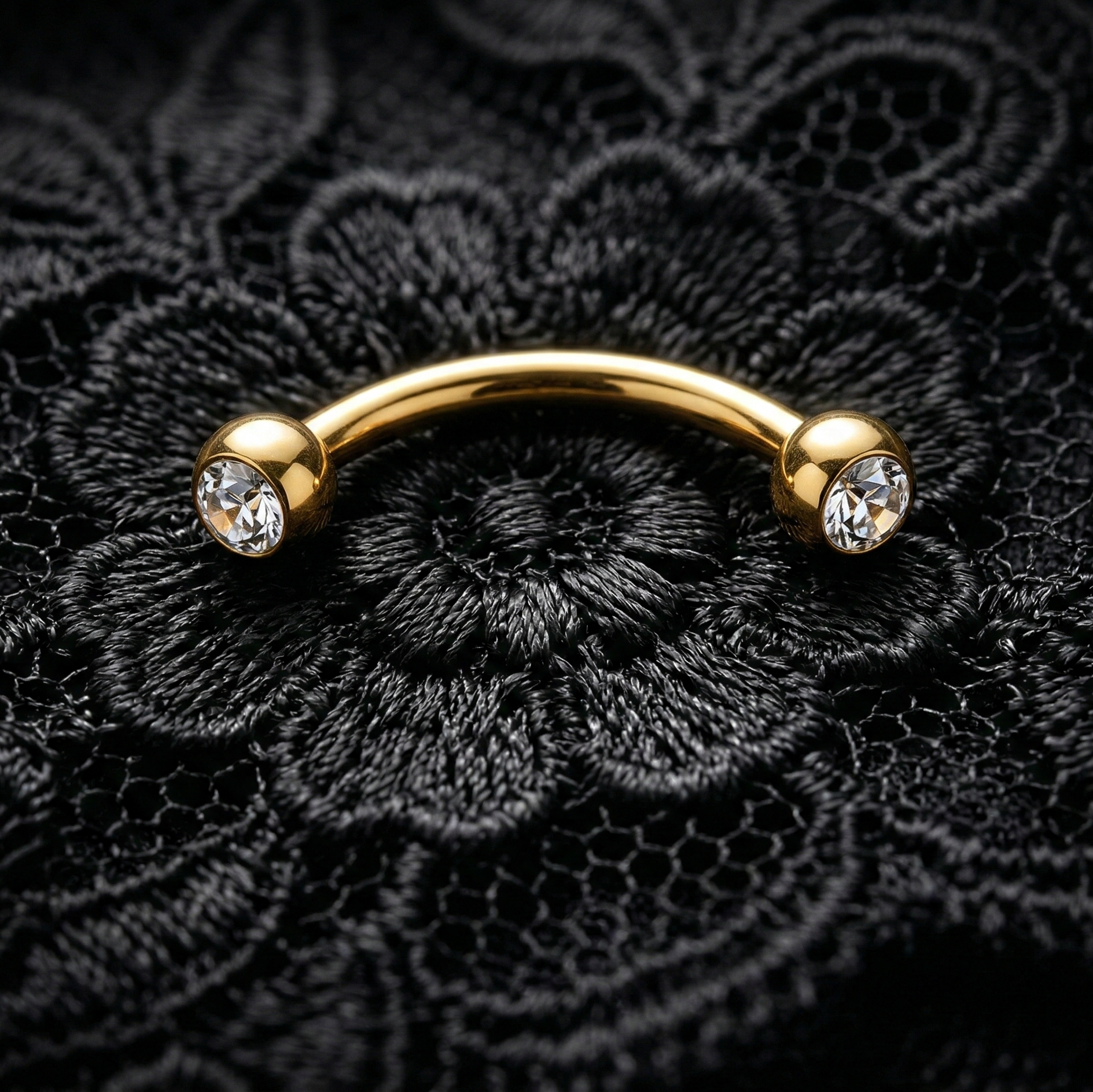 Gold eyebrow/rook barbell with crystals on a black lace background