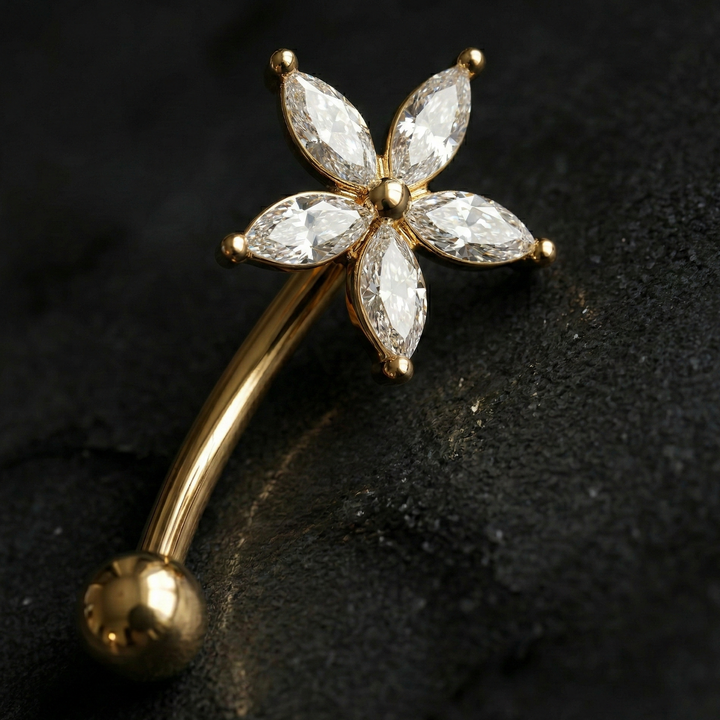 Gold eyebrow/rook barbell with diamond-like stone on a dark background