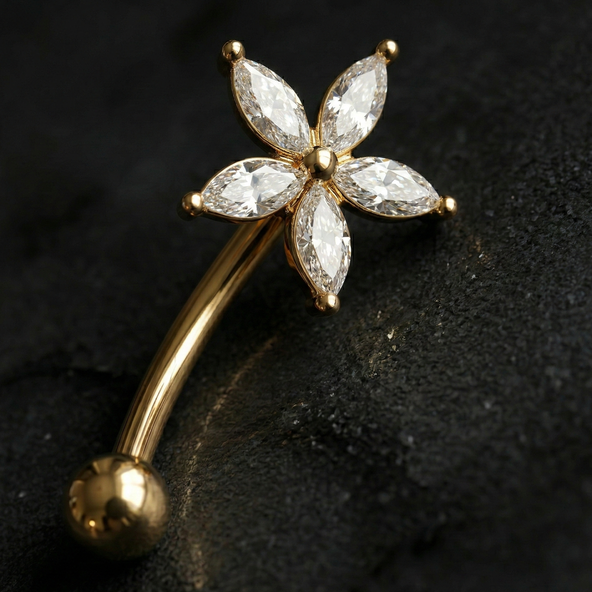 Gold eyebrow/rook barbell with diamond-like stone on a dark background
