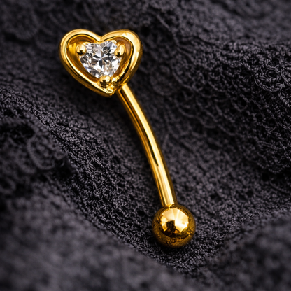 Gold eyebrow/rook barbell with heart-shaped top on a black textured background