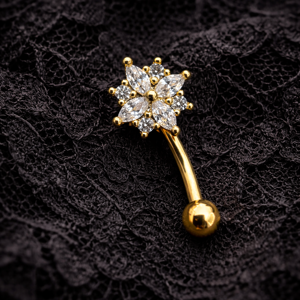 Gold eyebrow/rook barbell with star-shaped gemstones on a black textured background