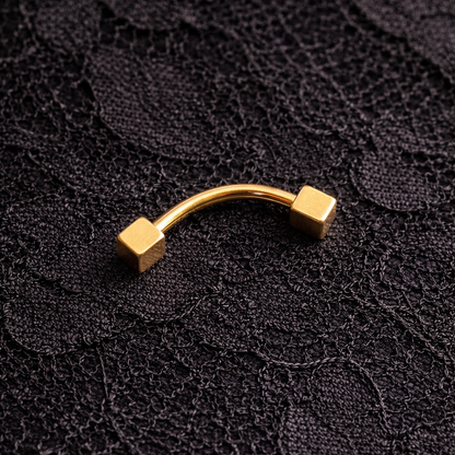 Gold eyebrow/rook curved barbell on a black textured background