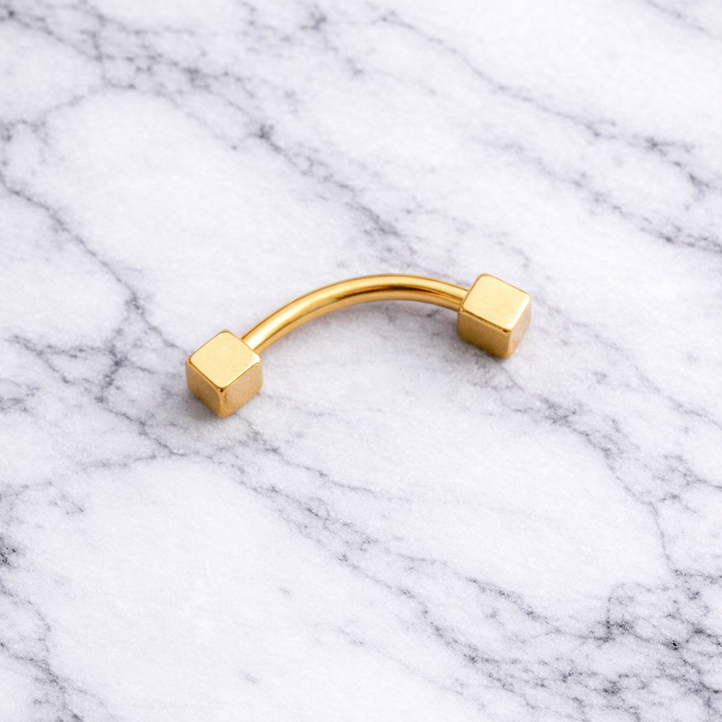 Gold eyebrow/rook piercing barbell on a marble background