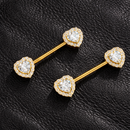 Gold heart-shaped nipple rings with clear gemstones on a black leather background