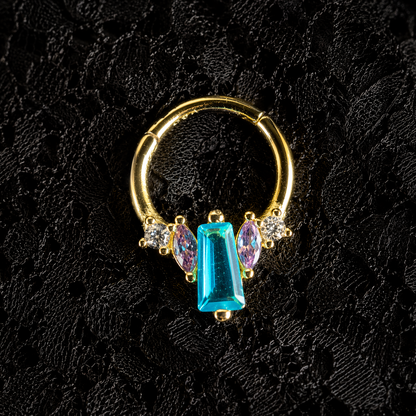 Gold hoop earring with blue and purple gemstones on a black textured background