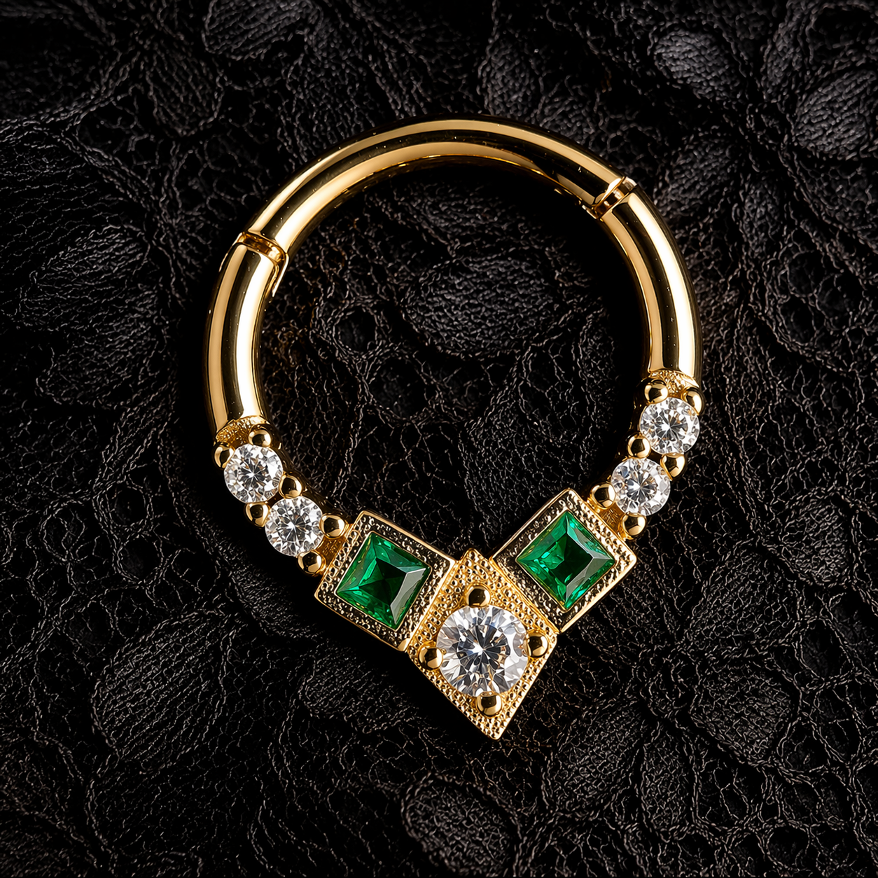 Gold hoop earring with emeralds and diamonds on a black lace background