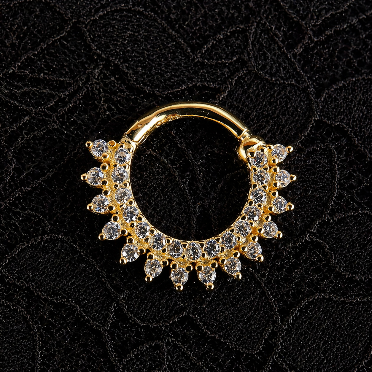 Gold hoop earring with gemstones on a black textured background