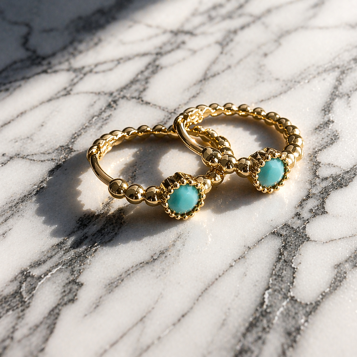 Gold rings with turquoise stones on a marble surface