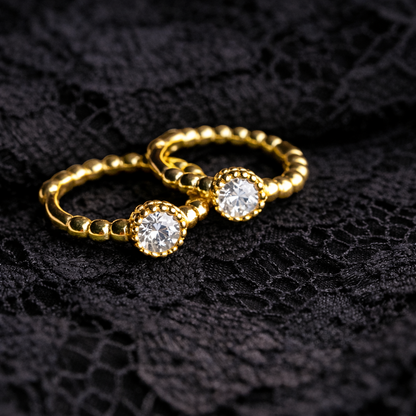 Gold ring with two clear gemstones on a black textured background