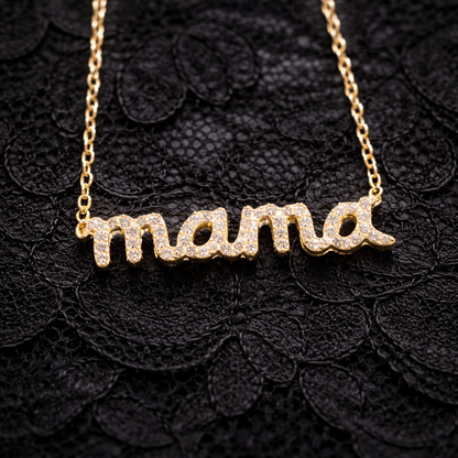 Gold 'mama' necklace on a black textured background
