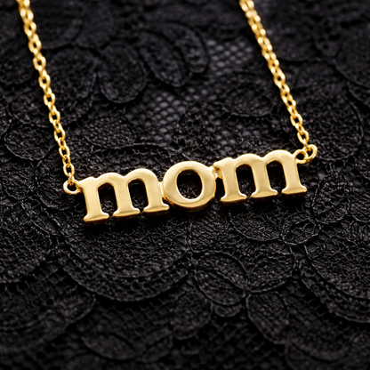 Gold 'mom' necklace on a black lace background