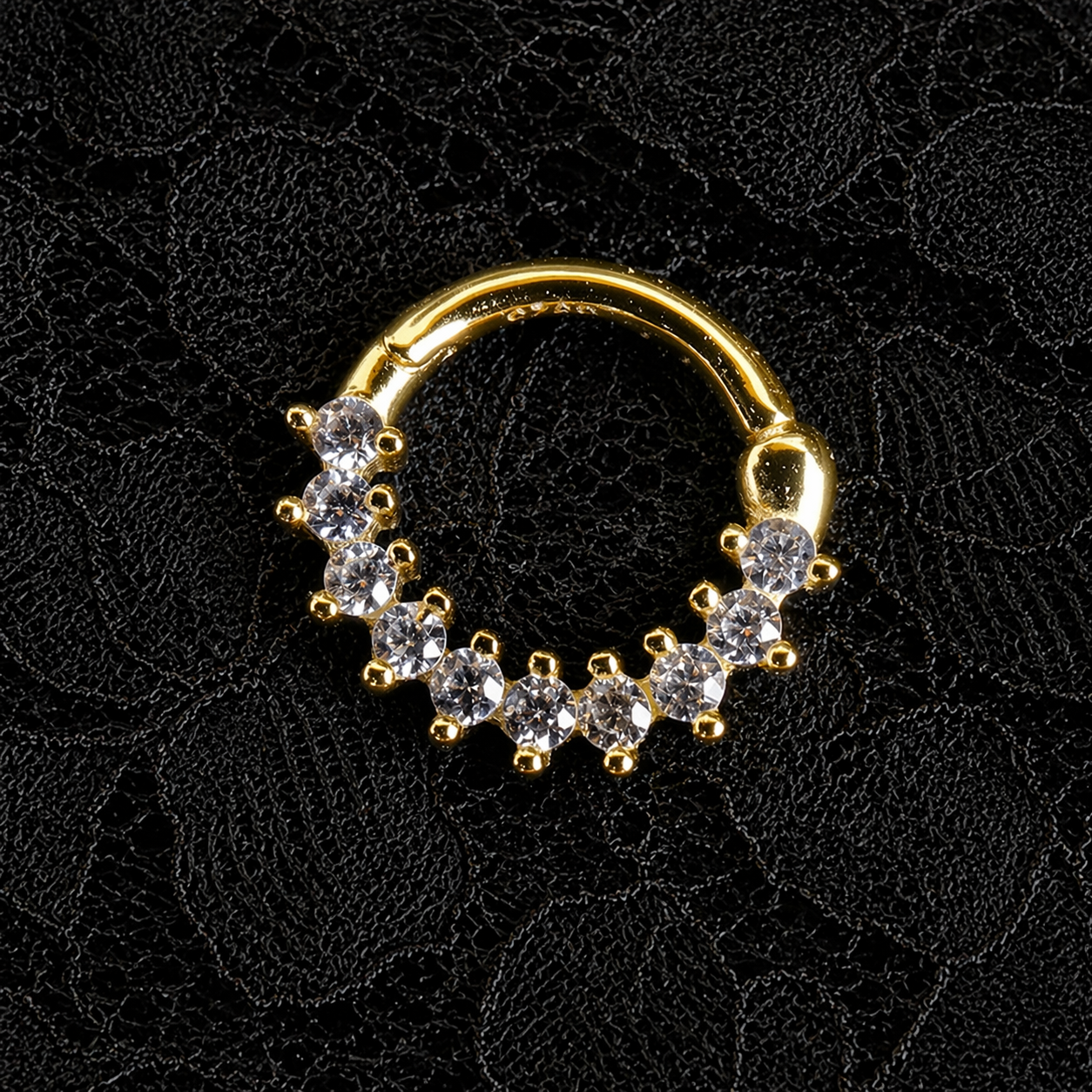 Gold nose ring with embedded stones on a black lace background