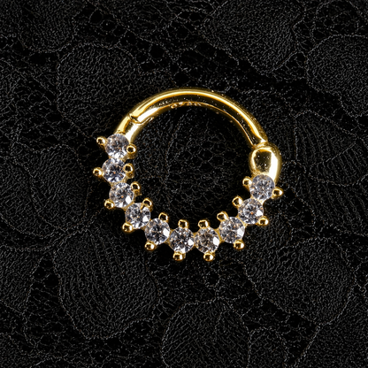 Gold nose ring with embedded stones on a black lace background