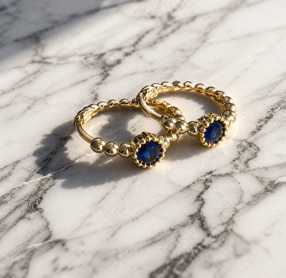Gold ring with blue gemstones on a marble surface