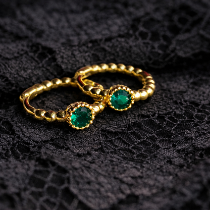 Gold rings with green gemstones on a black lace background