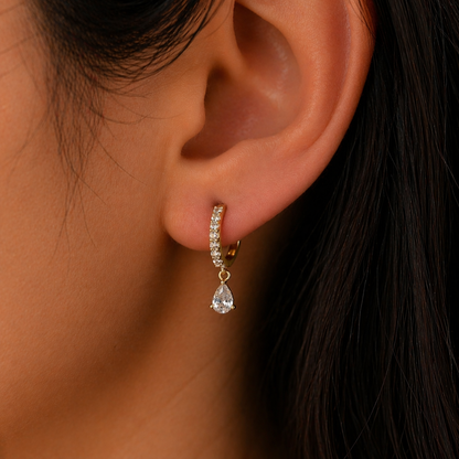 Close-up of an ear wearing a diamond earring with a dark background
