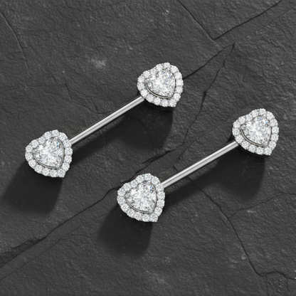 Heart-shaped diamond nipple piercing bars on a dark stone surface