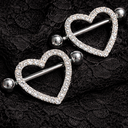 Heart-shaped nipple bars with clear gemstones on a black lace background