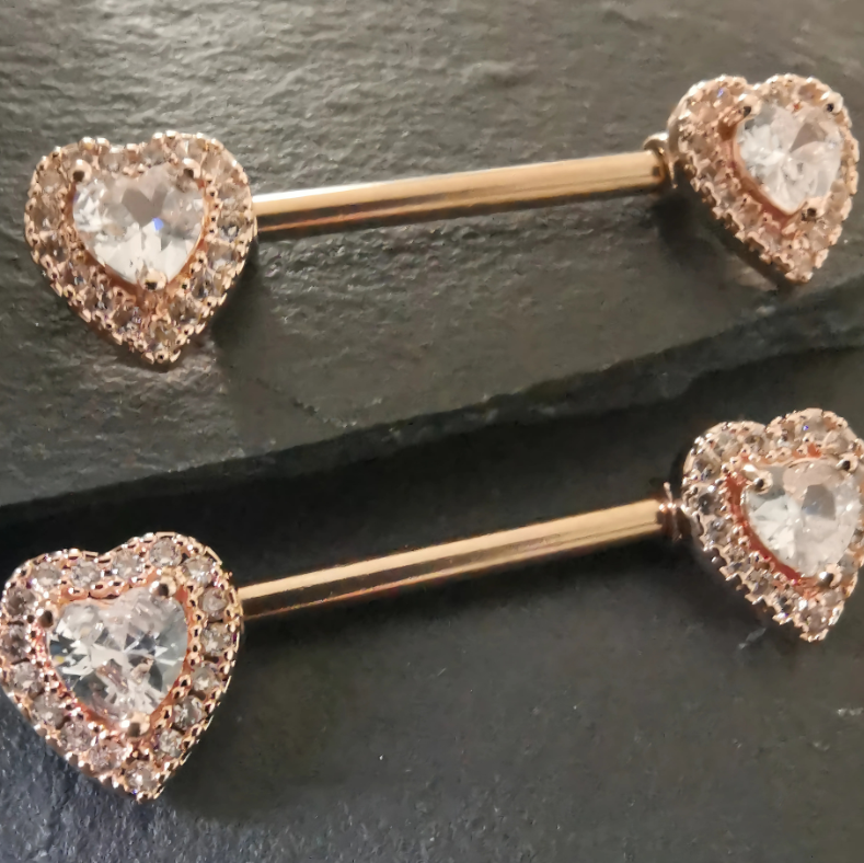 Heart nipple bar piercing in 14G rose gold surgical steel 316L with sparkling cubic zirconia accents.
