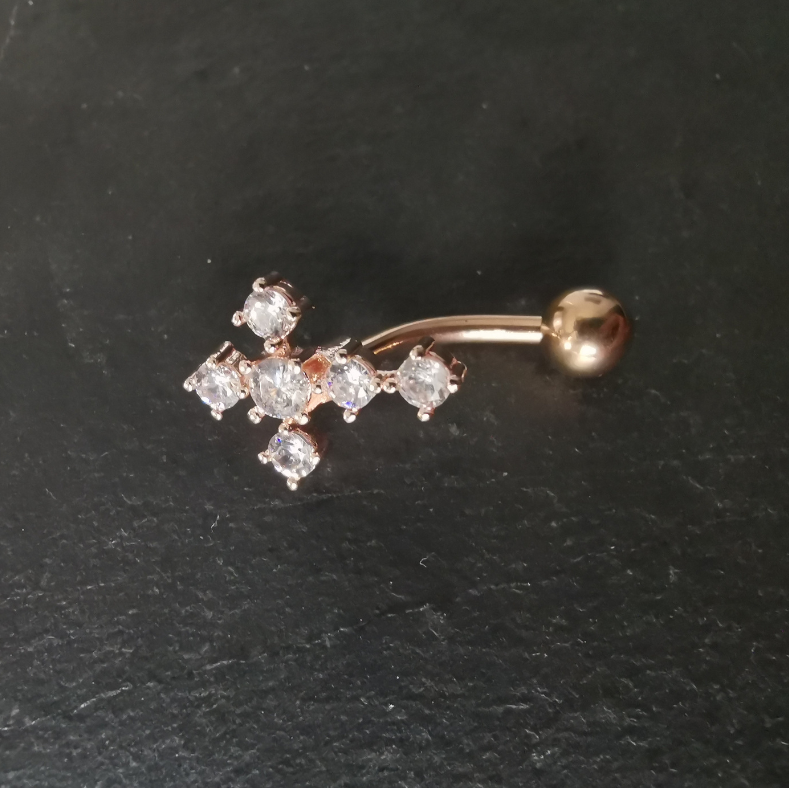 Close-up of rose gold belly button piercing with inverted cross design, crafted from high-polish 316L surgical steel for safe, hypoallergenic wear.