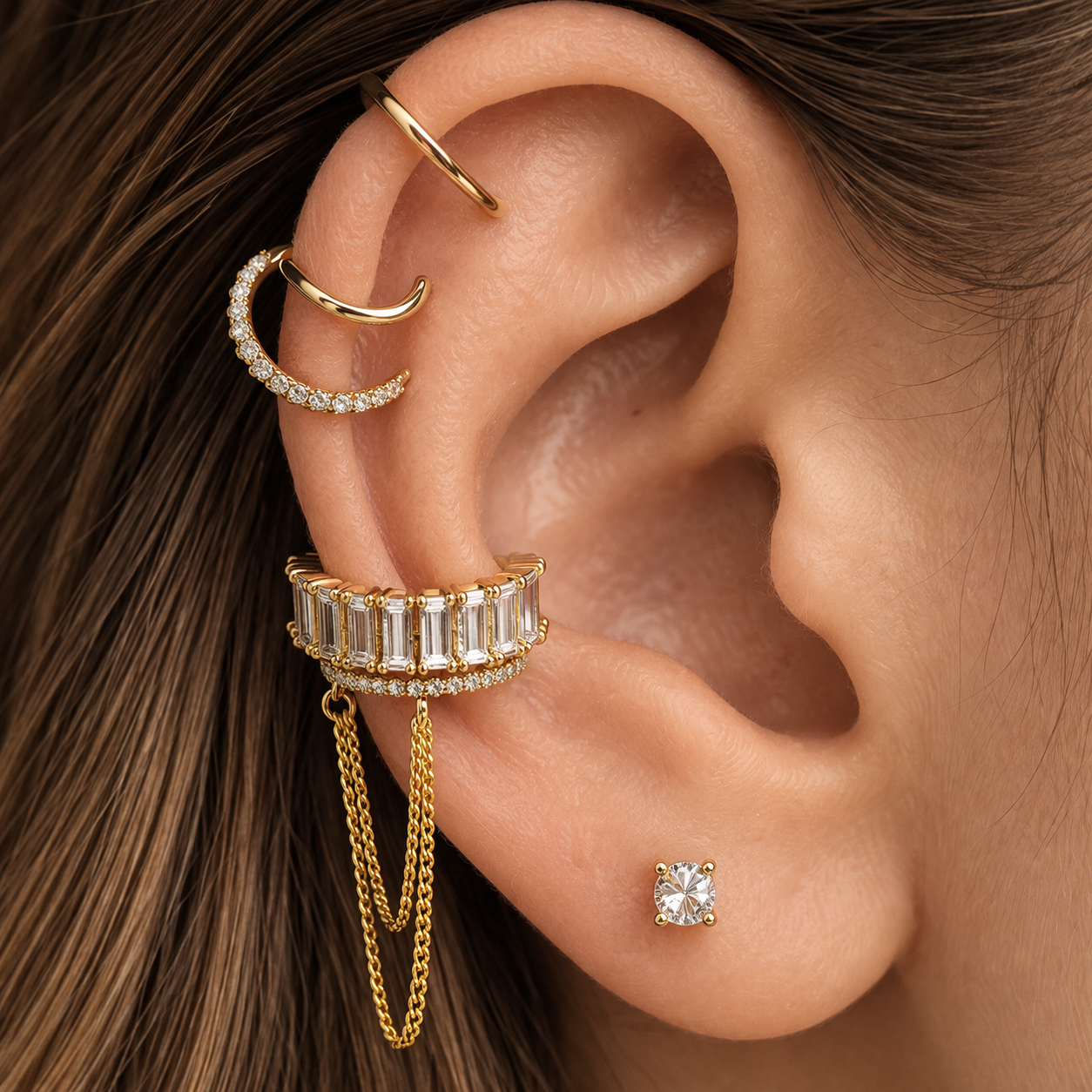Close-up of an ear with multiple gold and diamond earrings.